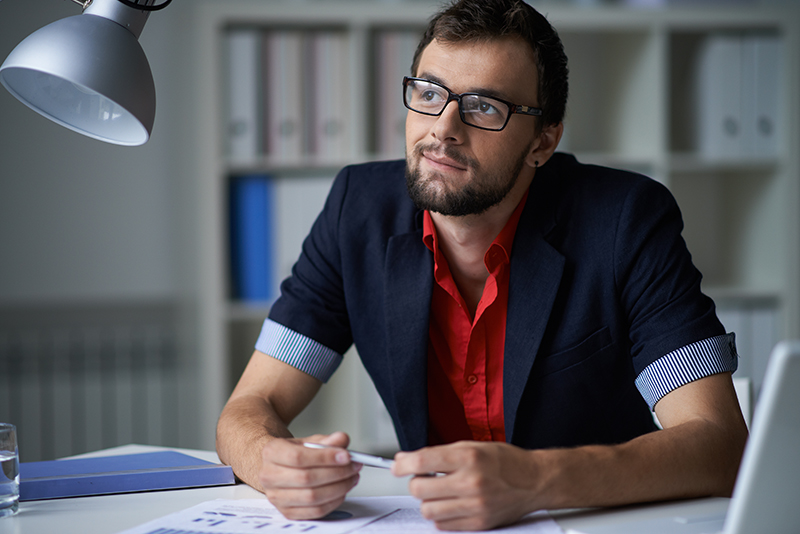 Handsome businessman in smart casual and eyeglasses thinking of idea in office